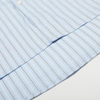 Close-up of a shirt with a button and collar detail on a light background