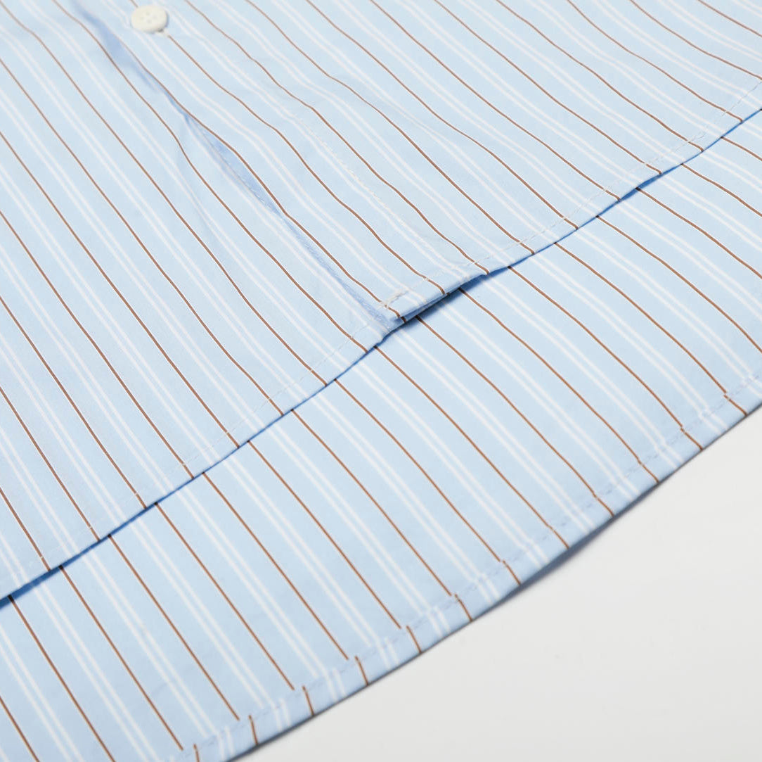 Close-up of a shirt with a button and collar detail on a light background