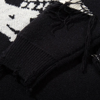 Black sweater with frayed edges on a patterned surface