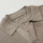 Close-up of a beige knitted polo shirt with buttons on a light gray background