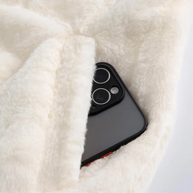 Phone case peeking out from a white fluffy blanket