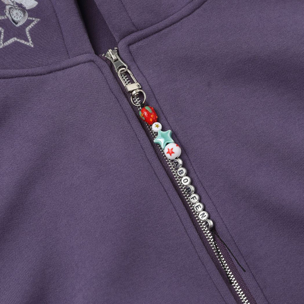 Close-up of a purple zip-up hoodie with decorative zipper pull featuring stars and numbers.