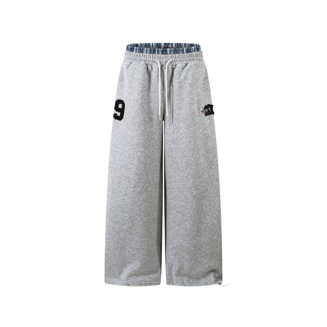 Gray sweatpants with a number 9 and logo on a white background