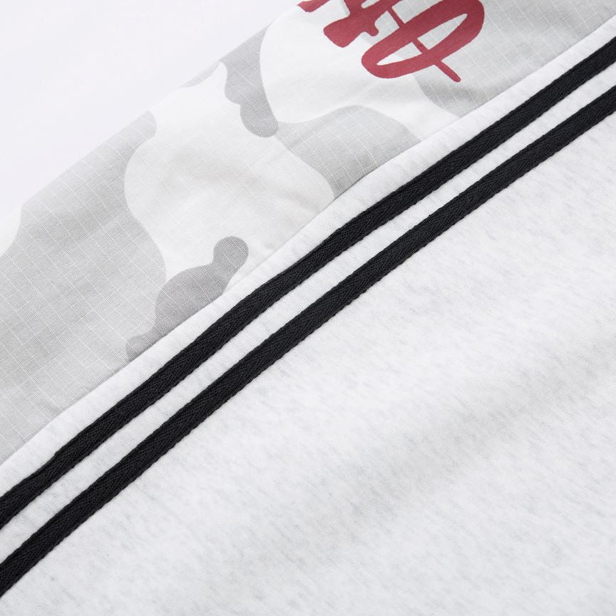 Close-up of a white garment with black stripes and red logo on a light gray background