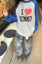 Person wearing a gray sweatshirt with 'I ❤️ emo' text and star-patterned pants in an indoor setting.