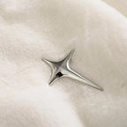 Silver star-shaped earring on a light fabric background