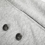 Close-up of a light heather gray fabric garment with two dark decorative buttons on the chest.