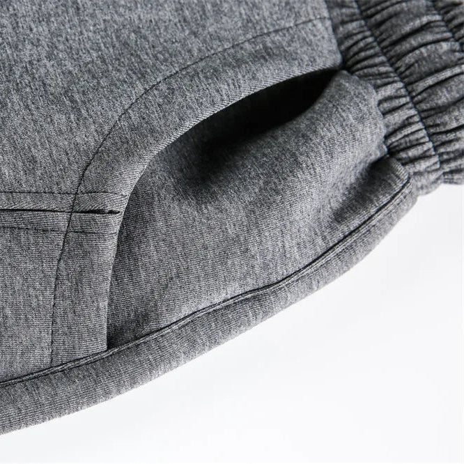 Close-up of a gray sweatpants fabric surface with a pocket detail on a white background