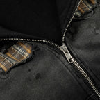Close-up of a black jacket with plaid accents and a zipper