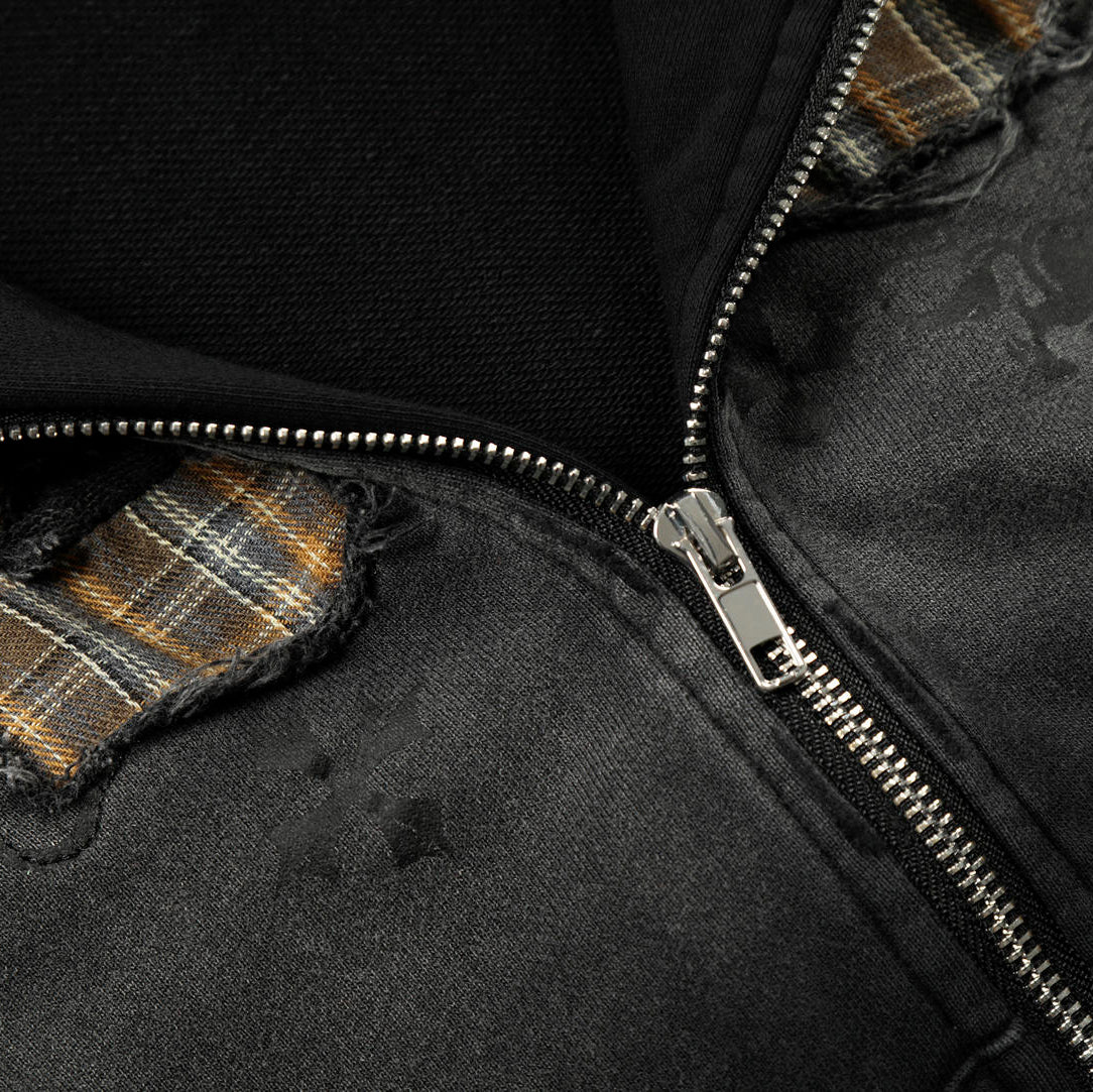 Close-up of a black jacket with plaid accents and a zipper