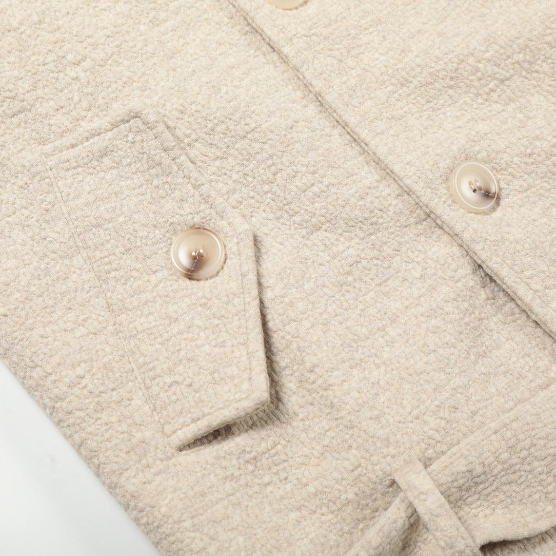 Close-up of a beige fleece jacket with buttons on a white background