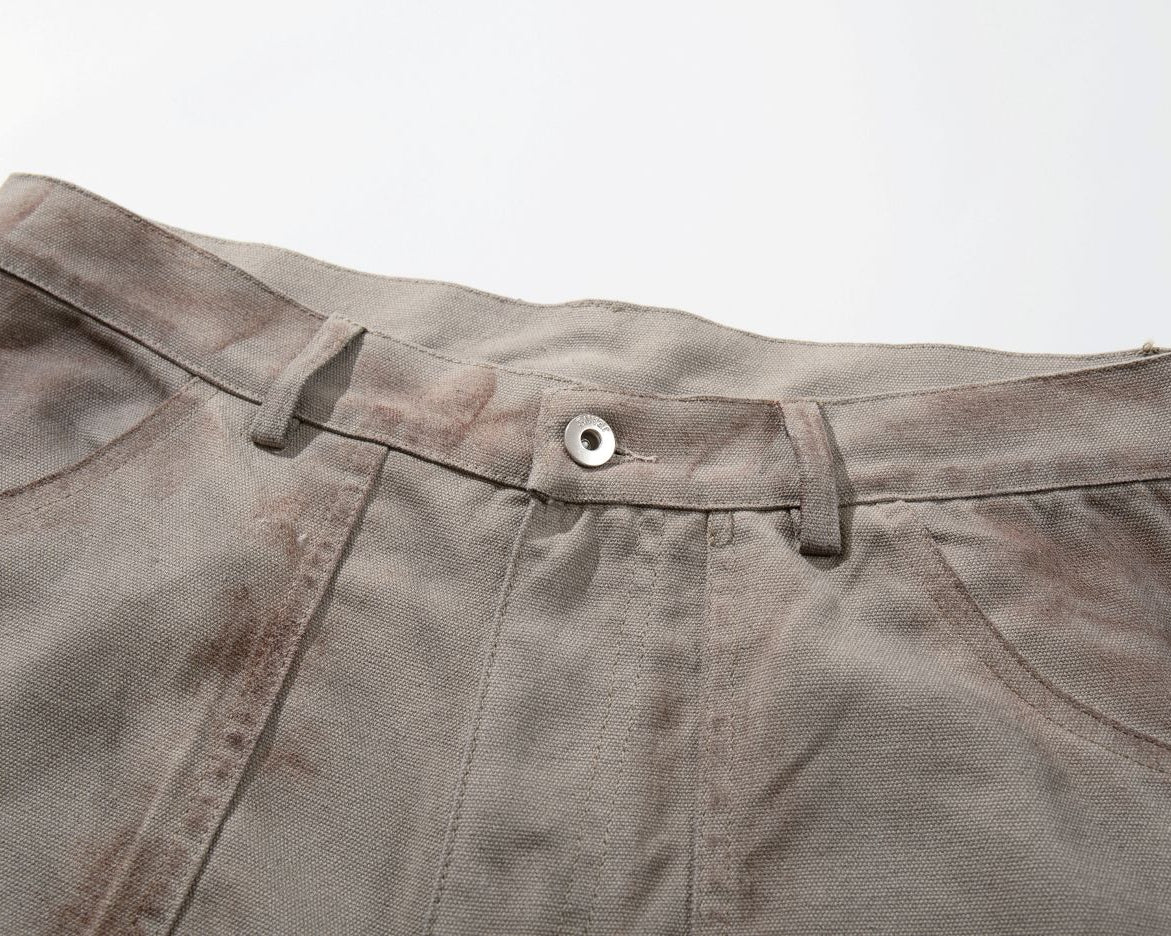 Close-up of a pair of brown pants with a button on a light gray background