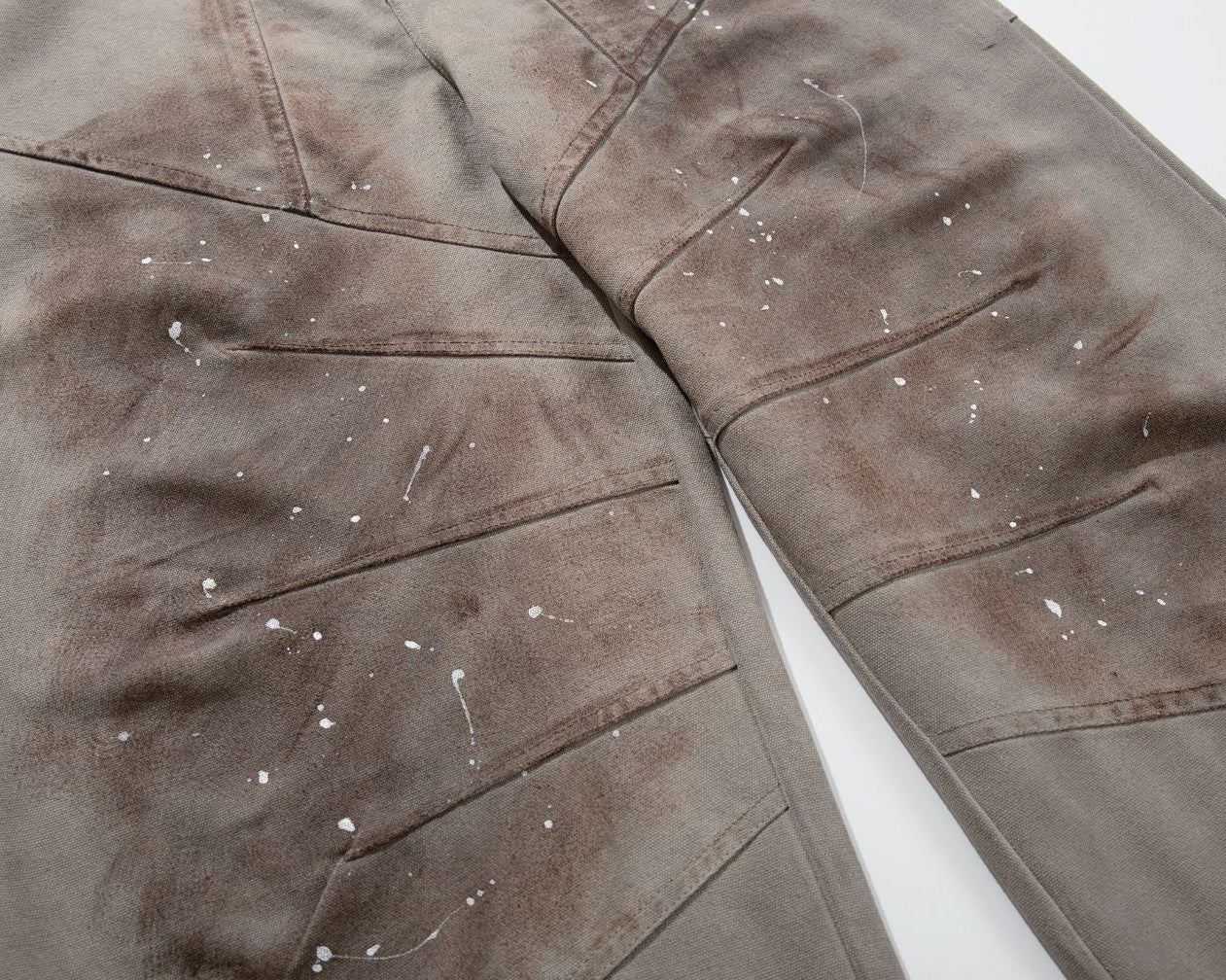 The Earth-Wash Paneled Wide-Leg Jeans with white specks on a white background