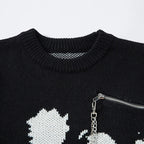 Black sweater with white star design and silver zipper on a light gray background