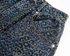 Close-up of blue denim fabric with a leopard print pattern on a white background