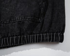 Close-up of a black denim jacket on a white background