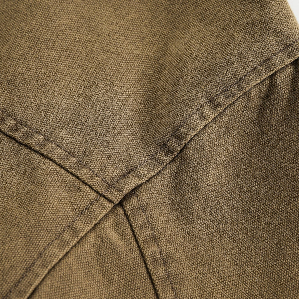 Close-up of brown fabric with stitching detail on a light gray background from h0neybear aka honeybear clothing